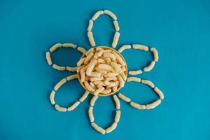 Corn sticks in a bowl in the shape of a flower on a blue background. Top view. Place for your text photo