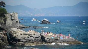 ligúria itália rochas da costa do mar - banho de sol de pessoas sentadas na rocha no dia de verão