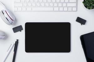 top view working desk with keyboard headphone and tablet on white table background photo