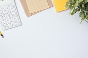 top view working desk with calculator and notebook on white table background photo