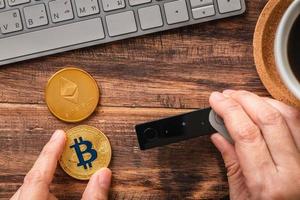 hand holding hardware wallet and transfer bitcoin and ethereum crypto currency to wallet for safety photo