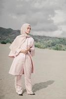 Beautiful islamic female model wearing hijab fashion, a modern wedding dress for muslim woman walks along the sand and the sea. A asian girl model using hijab having fun at the beach. Photo prewedding