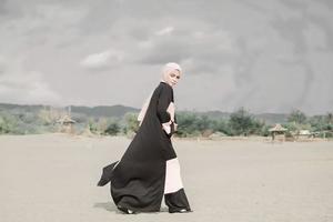 hermosa modelo femenina islámica con moda hijab, un vestido de novia moderno para mujeres musulmanas camina por la arena y el mar. una modelo asiática usando hijab divirtiéndose en la playa. foto preboda