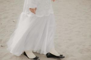 Beautiful islamic female model wearing hijab fashion, a modern wedding dress for muslim woman walks along the sand and the sea. A asian girl model using hijab having fun at the beach. Photo prewedding