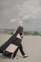 Beautiful islamic female model wearing hijab fashion, a modern wedding dress for muslim woman walks along the sand and the sea. A asian girl model using hijab having fun at the beach. Photo prewedding