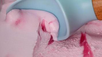 Close-up Strawberry ice cream scooped with blue spoon. Patterns and colors of ice cream. video