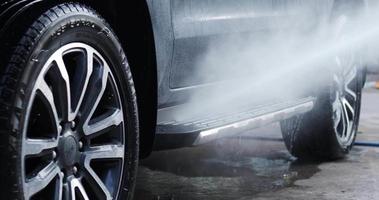 niebla de agua después de rociar las ruedas del automóvil para lavar. se esparció agua al automóvil mientras se rociaba. concepto de coche video