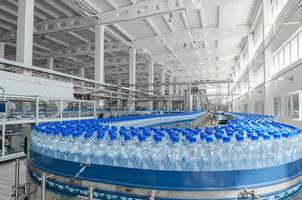 tashkent, uzbekistán - 7 de junio de 2016 - planta para la producción de botellas de plástico. botellas de plástico en una cinta transportadora. llenado de agua embotellada foto