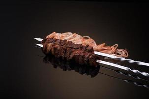 kebab sticks on skewers with onion and tomato on dark background photo