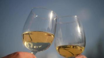 close-up de duas taças de vinho sendo brindadas no céu azul video