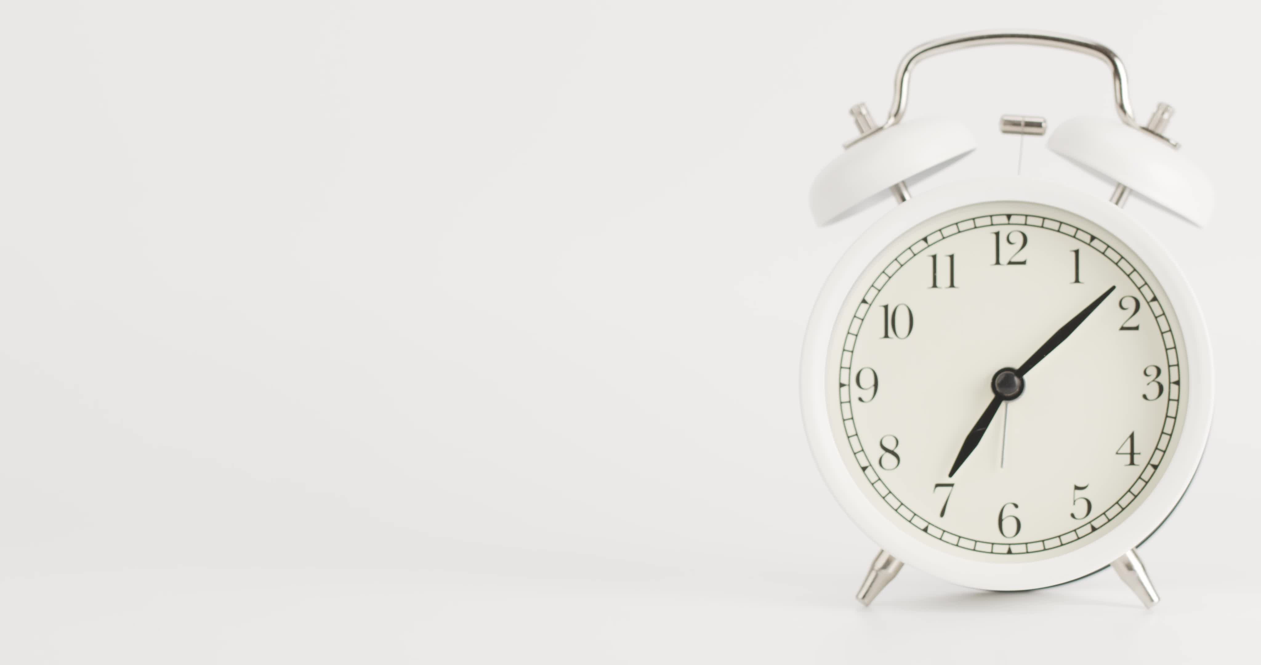 Zeitrafferweißer Wecker zeigt die Uhrzeit um 7 Uhr an. Die Uhr zeigt die verstrichene Zeit auf