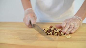 Bäcker schneidet mit Messer Haselnüsse für einen Kuchen video