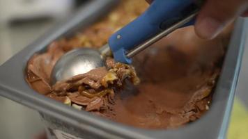 primo piano gelato al cioccolato al latte che esce dal contenitore in un cono video