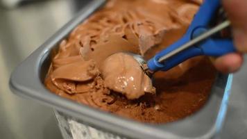 primo piano gelato al cioccolato al latte che esce dal contenitore in un cono video