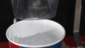 Hands pressing ice from ice machine for refill self service in Kentucky Fried Chicken or KFC fast food restaurant in thailand.