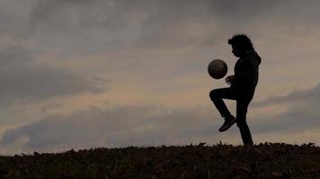 Kind in Silhouette dribbelt mit Fußball video