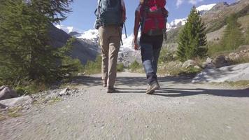 Alpine trekking. Detail of walking feet and legs of two friends mov