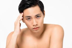 Un joven asiático guapo sin camisa con la mano tocando la cabeza aislado de fondo blanco para el cuidado de la piel y los conceptos de belleza