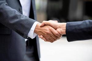 Businessman in formal suit making handshake with partner outdoors photo