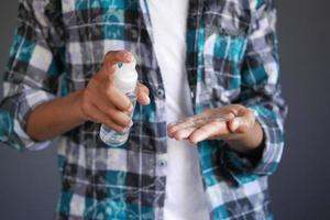 close up of young man hand using hand sanitizer spray. photo