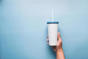 holding reusable eco coffee cup on blue with copy space. photo