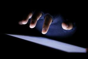 Close up of hacker hand stealing data from digital tablet photo