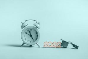Yellow alarm clock with graduation cap on blue background closeup with copy space photo