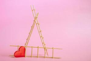 Wooden ladder with red hearts on a pink background. Postcard or invitation template. Closeup photo