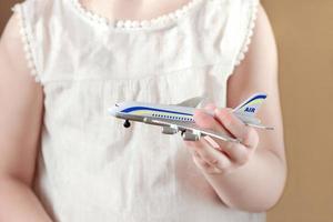 niña sosteniendo avión de juguete, vacaciones y concepto de seguridad de aviones. foto