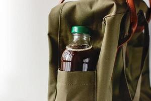 café frío para llevar. bebida fría en una botella en el bolsillo de la mochila. foto