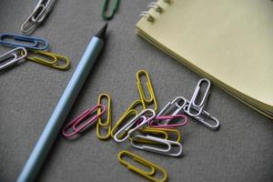 Pencils notepad and paper clips on the office desk photo