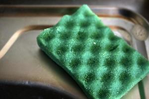 Green sponge for washing dishes in the kitchen photo