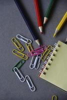Pencils notepad and paper clips on the office desk photo