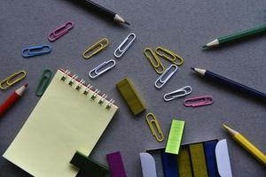 Pencils notepad and paper clips on the office desk photo