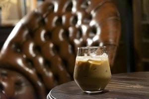 vaso de café con leche helado sobre un fondo de tono marrón oscuro foto