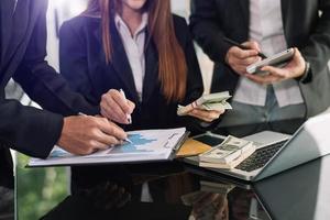 Business documents on office table with smart phone and calculator digital tablet and graph business with social network diagram and two colleagues discussing data working in the office photo