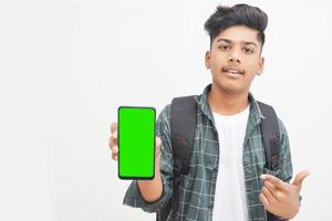 joven estudiante universitario indio que muestra la pantalla del teléfono inteligente con fondo blanco. foto