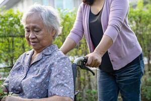 Caregiver help Asian senior or elderly old lady woman on wheelchair in park. photo
