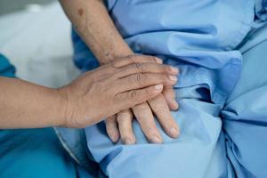 Tomados de la mano anciana asiática o anciana paciente con amor, cuidado, ánimo y empatía en la sala del hospital de enfermería, concepto médico fuerte y saludable foto