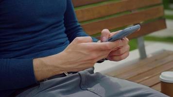 Writing a message on smartphone outdoor park. video