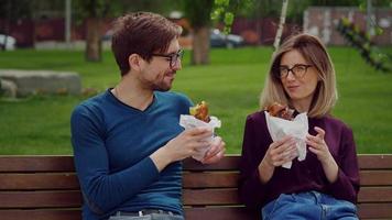 uomini d'affari che fanno uno spuntino con cibo da asporto in un parco. video