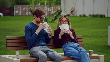 jonge zakenmensen met een snack met afhaalmaaltijden in een park. buiten eten. video