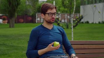 homem bonito comendo comida saudável, desfrutando de uma fruta no parque.