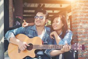 Hipster couple sitting relaxed with nice atmosphere with first date enjoys playing guitar as a great time together. photo