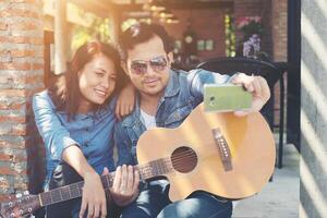 una pareja hipster sentada relajada con un ambiente agradable con la primera cita disfruta tocando la guitarra como un gran momento juntos. foto