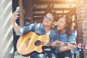 Hipster couple sitting relaxed with nice atmosphere with first date enjoys playing guitar as a great time together. photo