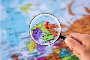 hand holding Magnifying Glass in front of map find Finland photo