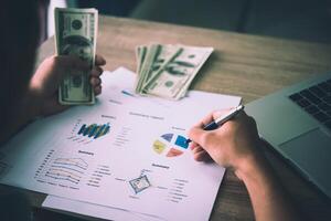 Working place of trader. The table covered by cash notes, keyboard and financial charts. Business financial working. photo