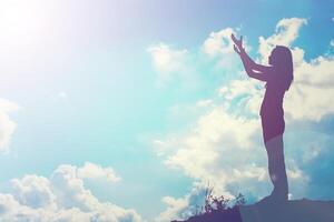 Silhouette of woman praying over beautiful sky background photo