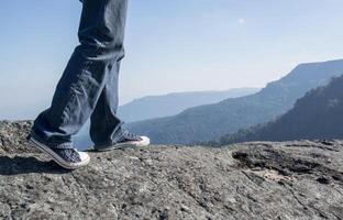 Man walking on edge of a cliff mountain top , travel concept photo